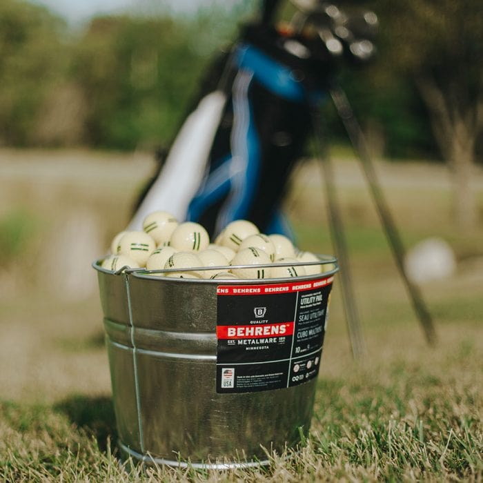 Behrens Metalware Classics Galvanized Steel Pail filled with golf balls with a golf cart in the back ground