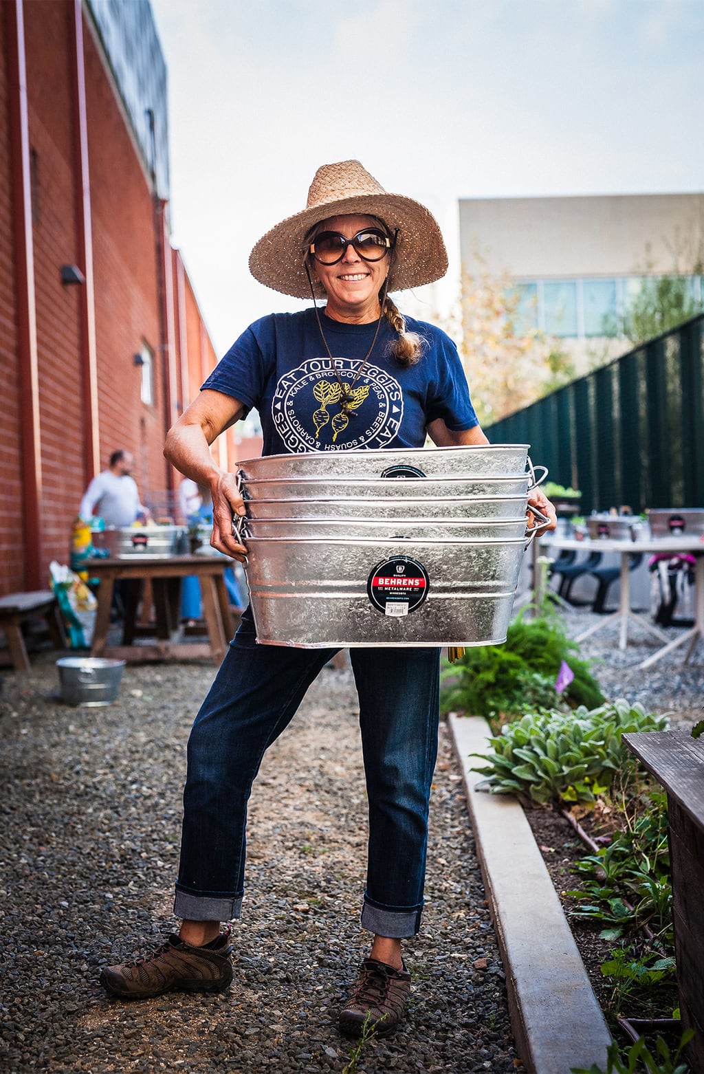 A woman holding a stack of galvanized steel tubs