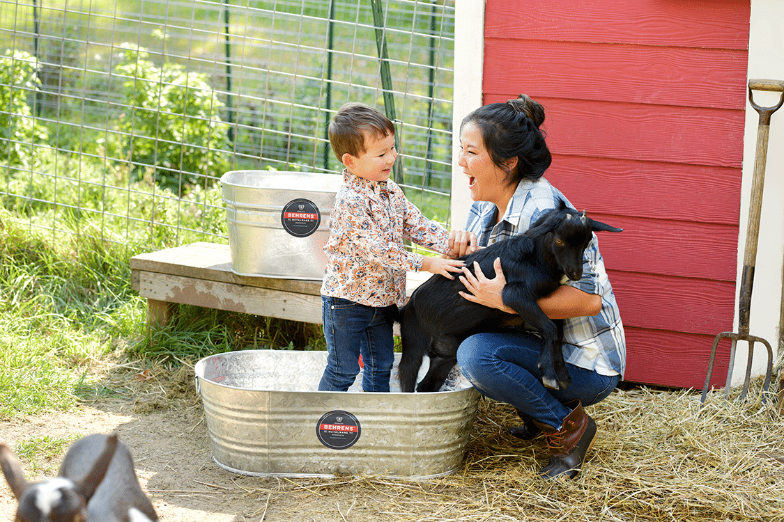 woman playing with her son who is in a Behrens metal tub