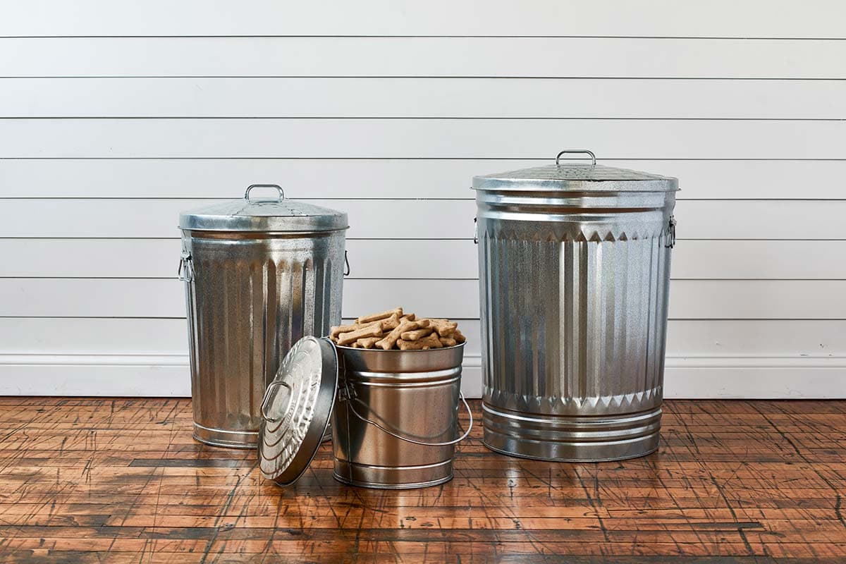 A short , medium, and large galvanized steel cans with dog food in the shortest can.