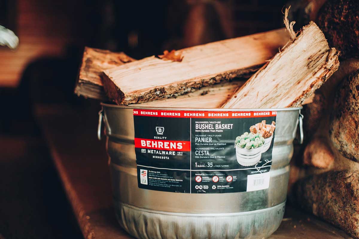 Galvanized steel bucket holding chopped wood by a fireplace