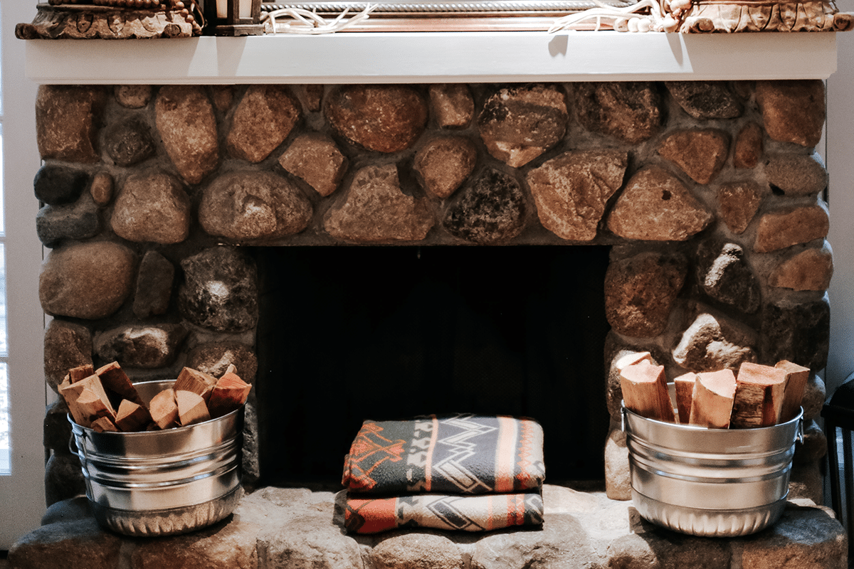 blankets on the mantel of fireplace with galvanized steel bushel baskets filled with wood